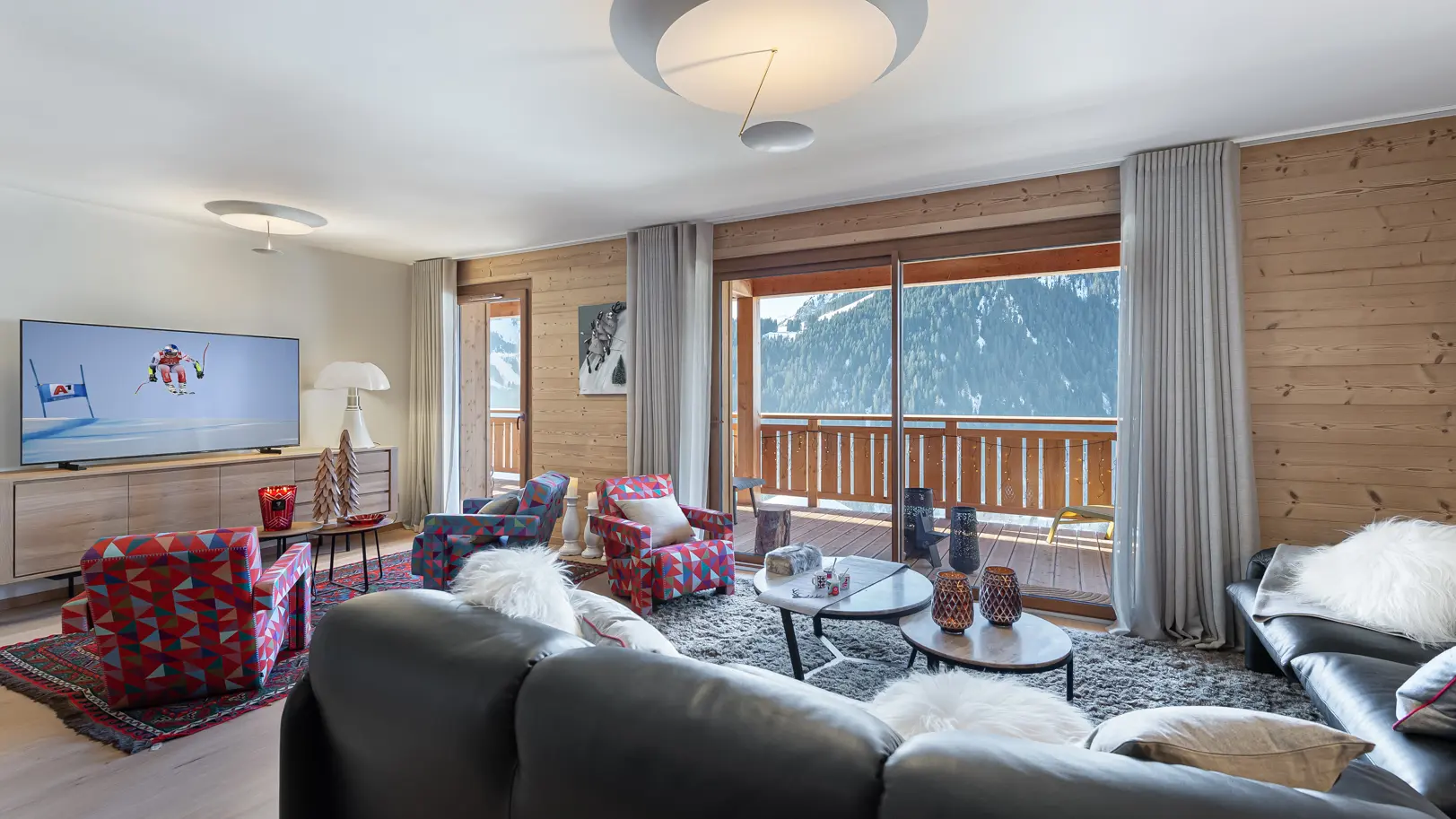 Vue d'ensemble du salon, canapés, fauteuils, télévision, accès au balcon