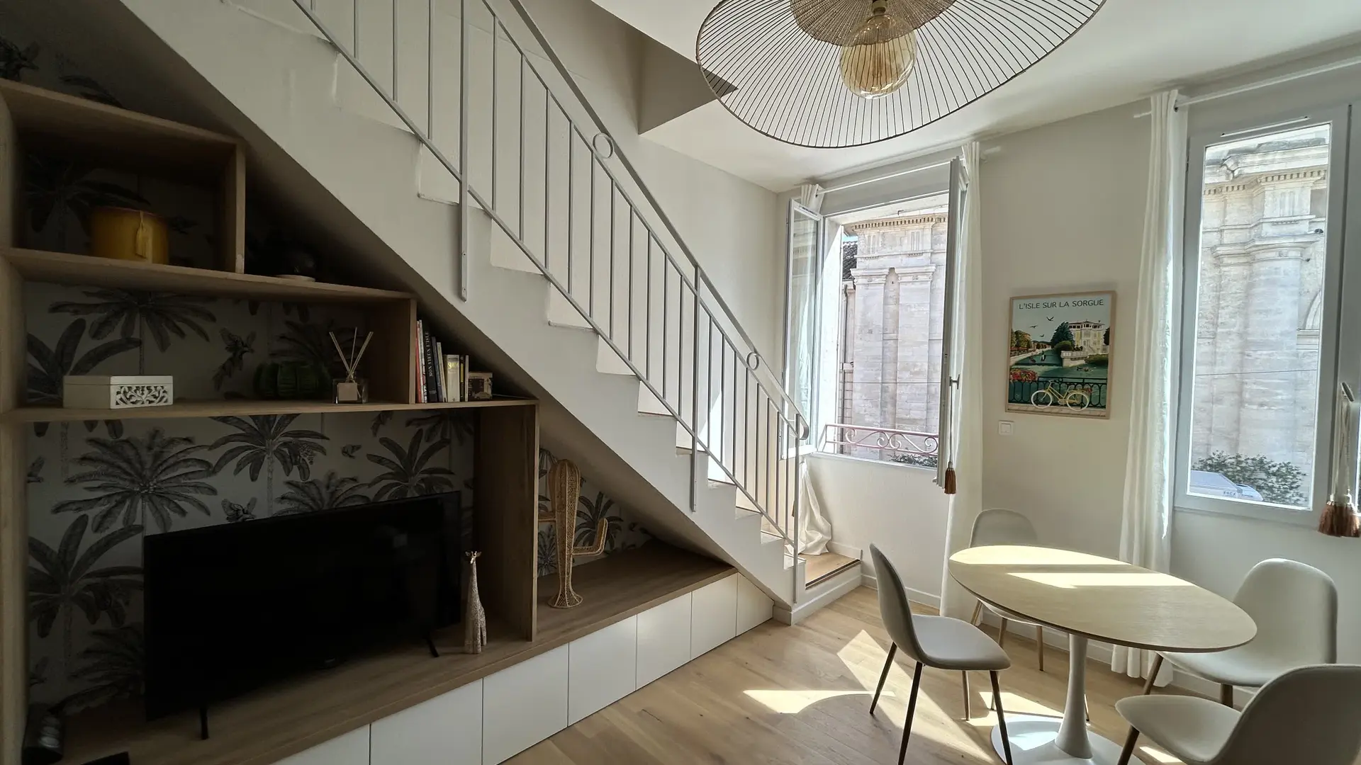 Un vaste séjour structuré par un escalier aérien et un mobilier sur mesure, alliant fonctionnalité et esthétique moderne.