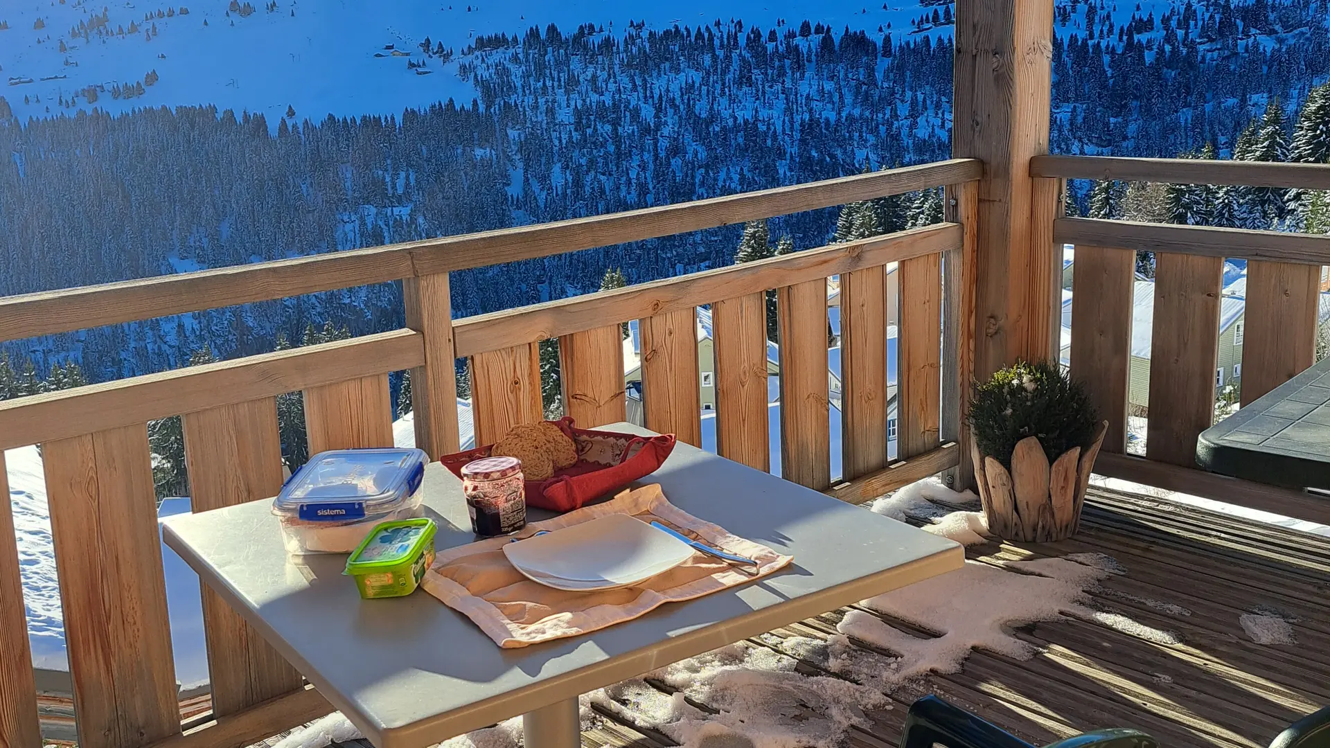 A sunny breakfast on a chalet terrace overlooking the snow-covered peaks.
