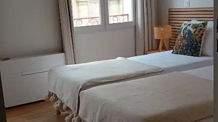 Une chambre aux tons naturels, pensée pour le repos, avec deux lits confortables et une décoration sobre et raffinée.