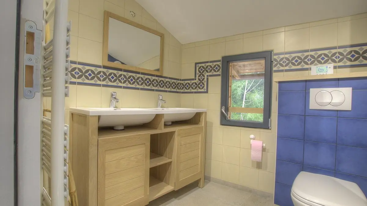 Salle d'eau avec double vasques et WC intégré.