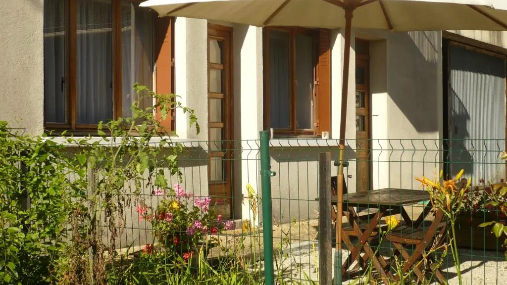 La terrasse, adossée à la maison, est équipée d'un store banne et meublée d'une table et de chaises.