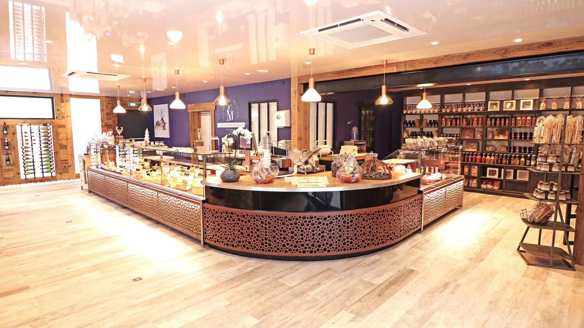 Entrée du magasin des Délices de Margot, avec un comptoir arrondi au premier plan et des étagères avec des produits dans le fond.