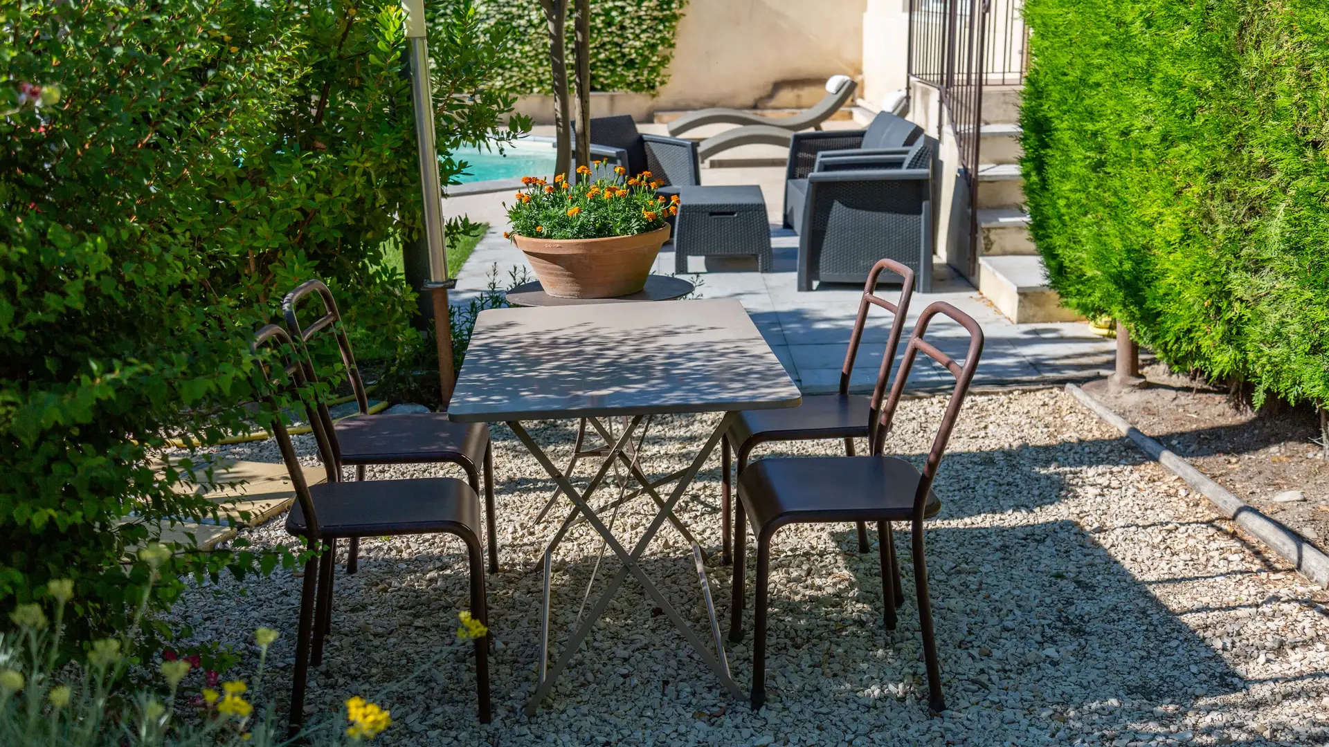 Une table extérieure entourée de verdure, idéale pour partager un repas ou un café à l’ombre, dans une atmosphère paisible et intimiste.