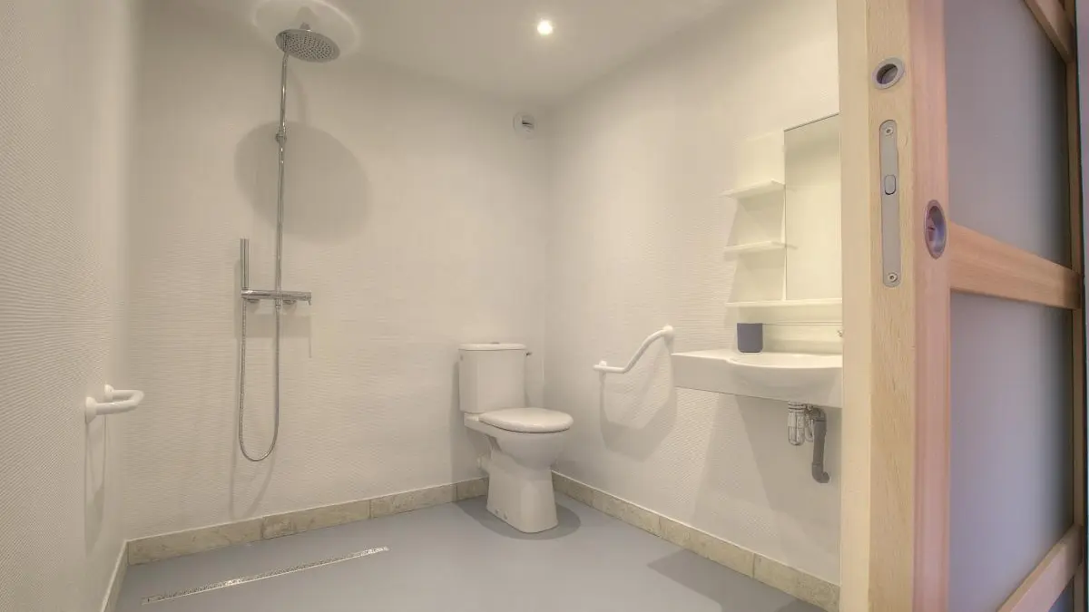 Salle d'eau privative à la chambre accessible aux personnes à mobilité réduite. Porte coulissante.