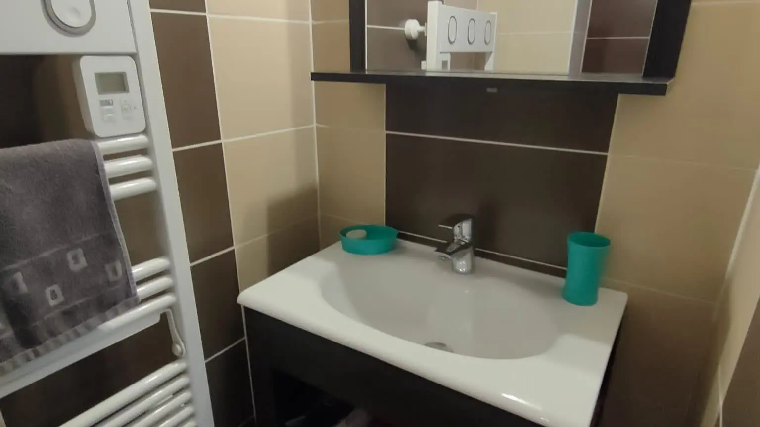 Meuble vasque avec miroir, rangements et sèche-serviettes pour un confort optimal.