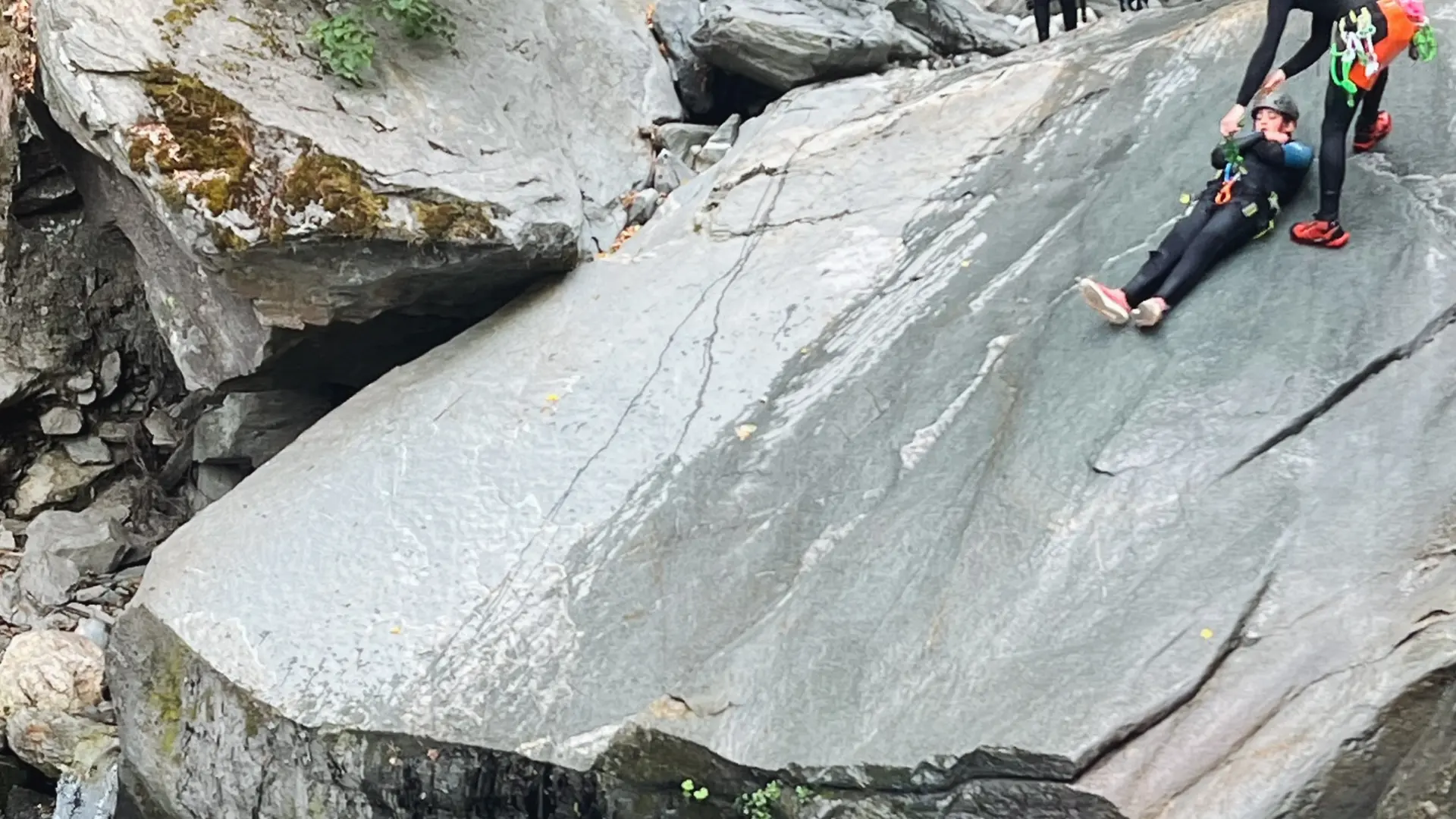 canyonistes glissant sur une dalle à eau rousse