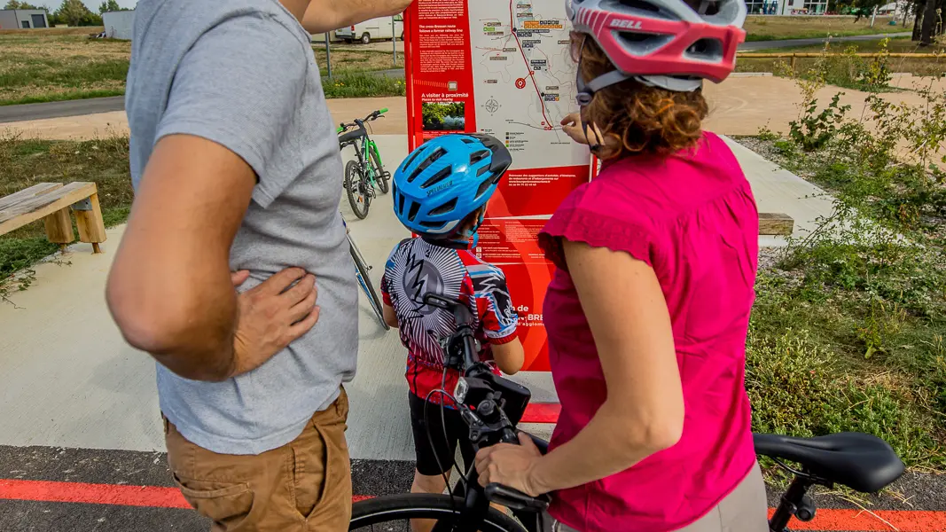 Une famille à vélo qui consulte le panneau d'information