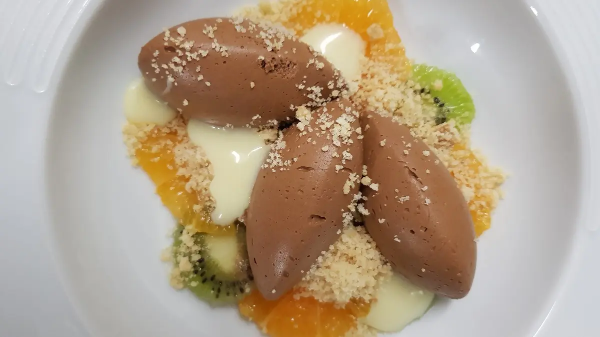 Dessert joliment présenté avec des kiwis, oranges et de la crème chocolat.