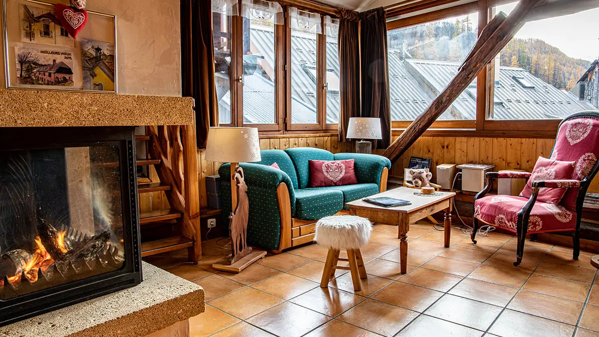 Warm and bright living room with sofa, armchairs, windows overlooking the village