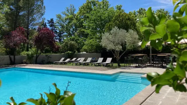 Une vaste piscine turquoise entourée de transats et de verdure pour un moment de détente.