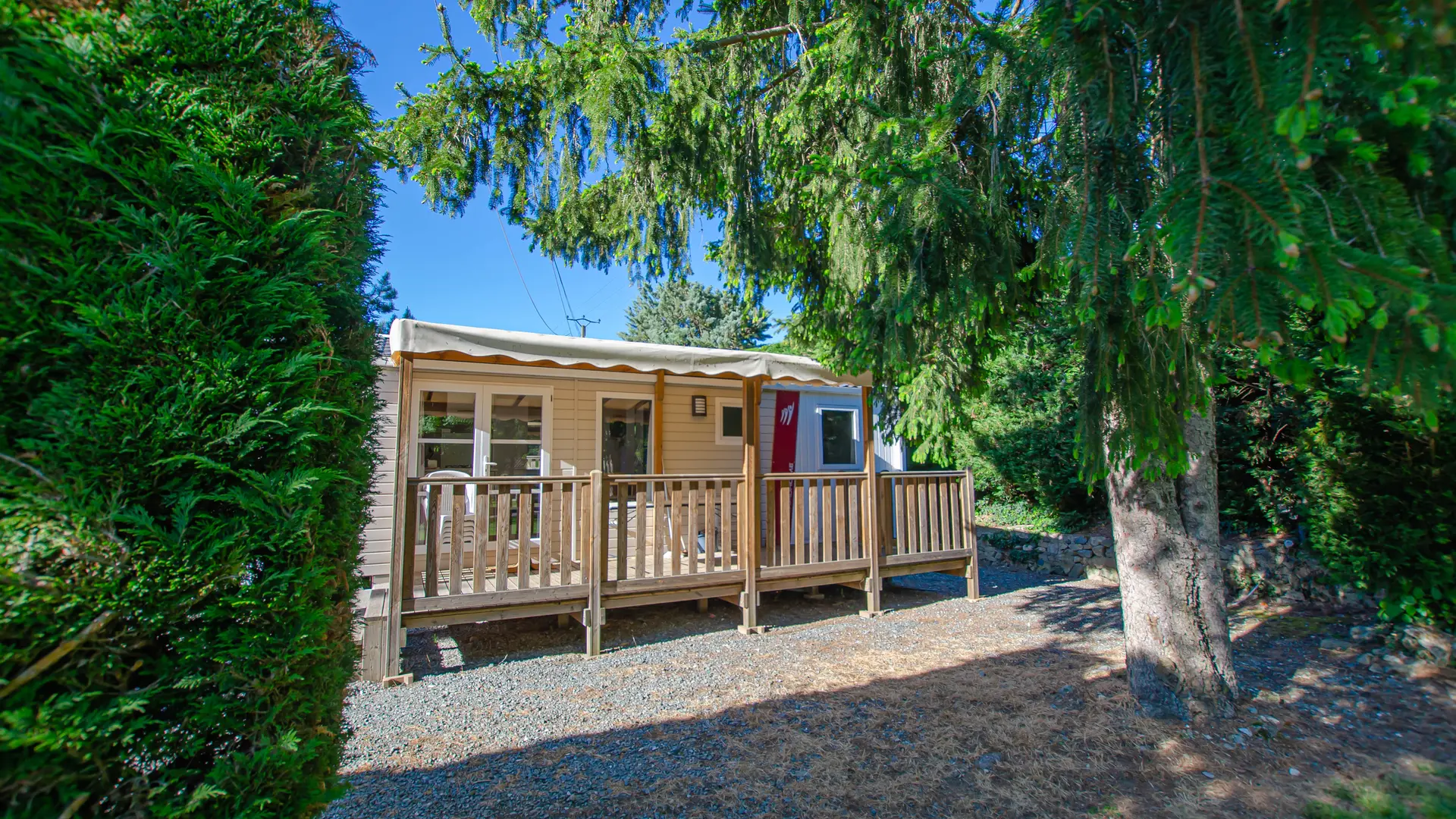 Le lodge est situé dans un environnement arboré, avec une terrasse en bois.