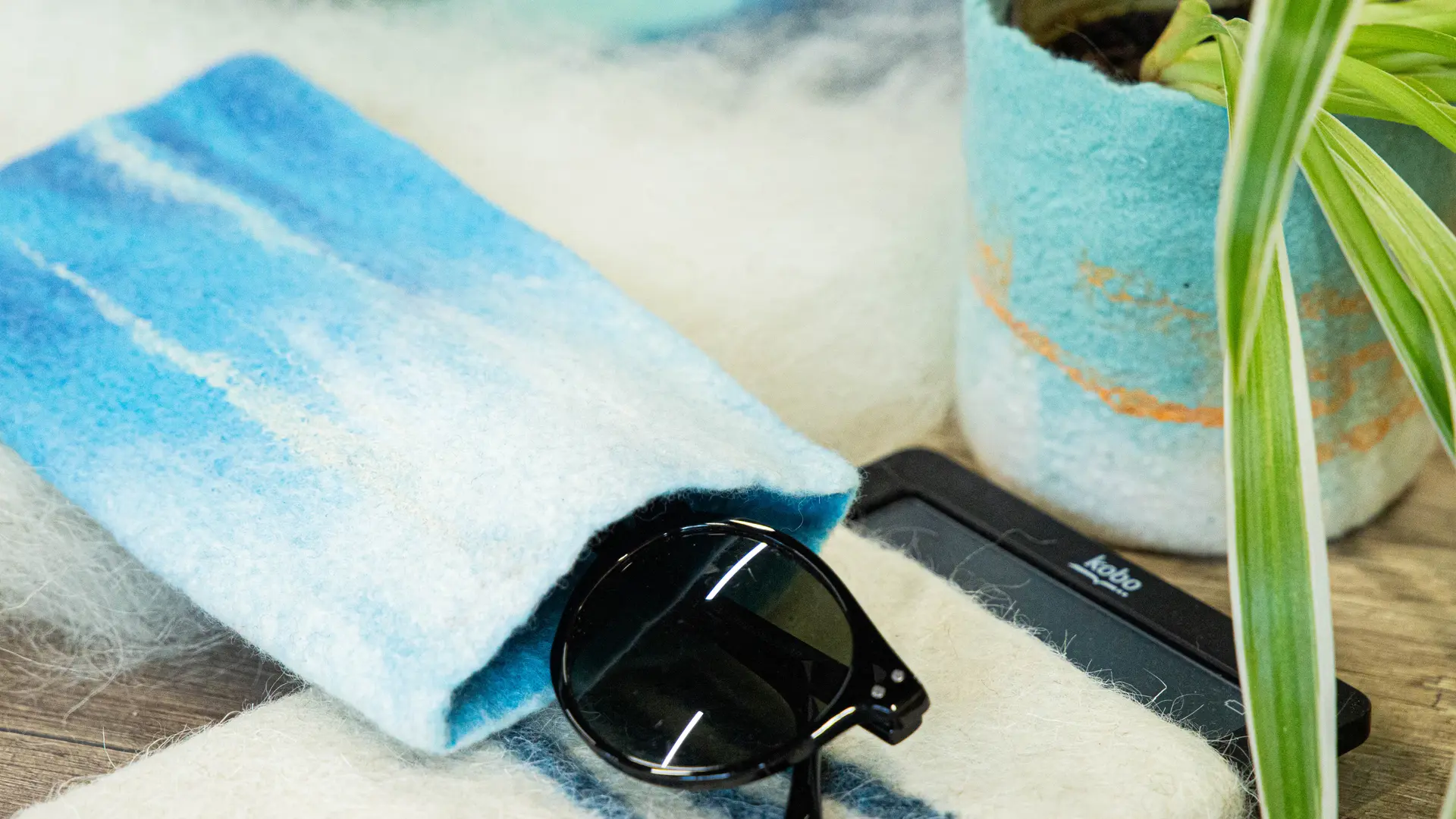 Une pochette à lunettes de soleil et un cache-pot contenant une plante