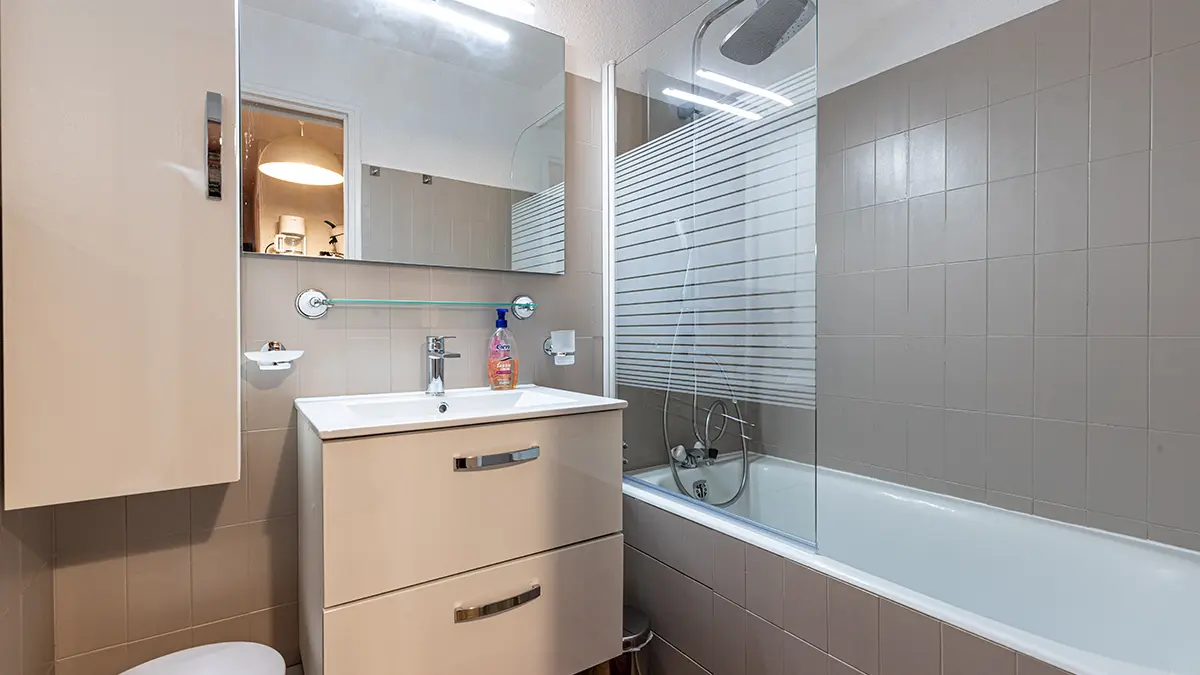 Modern tiled bathroom with bathtub, sink and mirror, cupboard