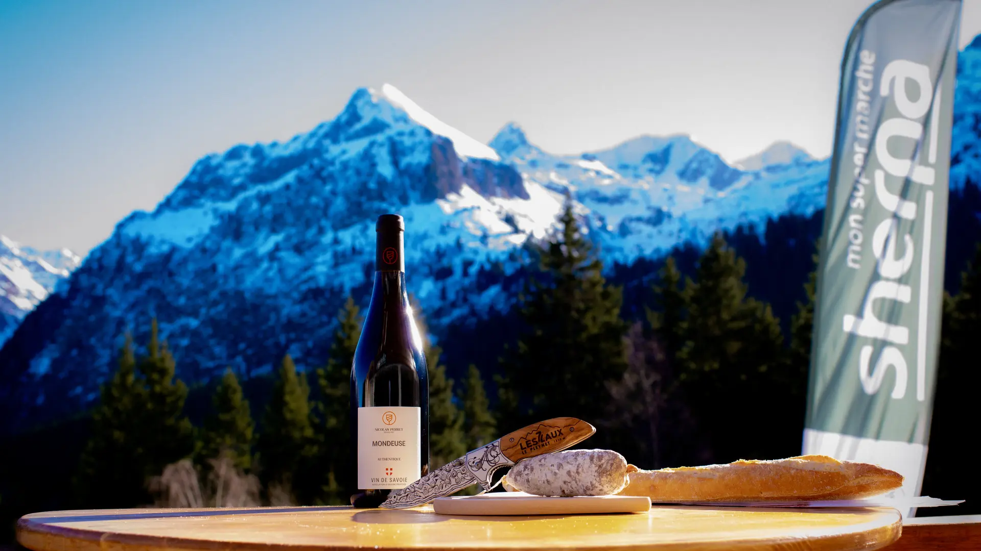 Planche apéro avec saucisson et vin savoyard vendus au Sherpa dans un décor montagnard