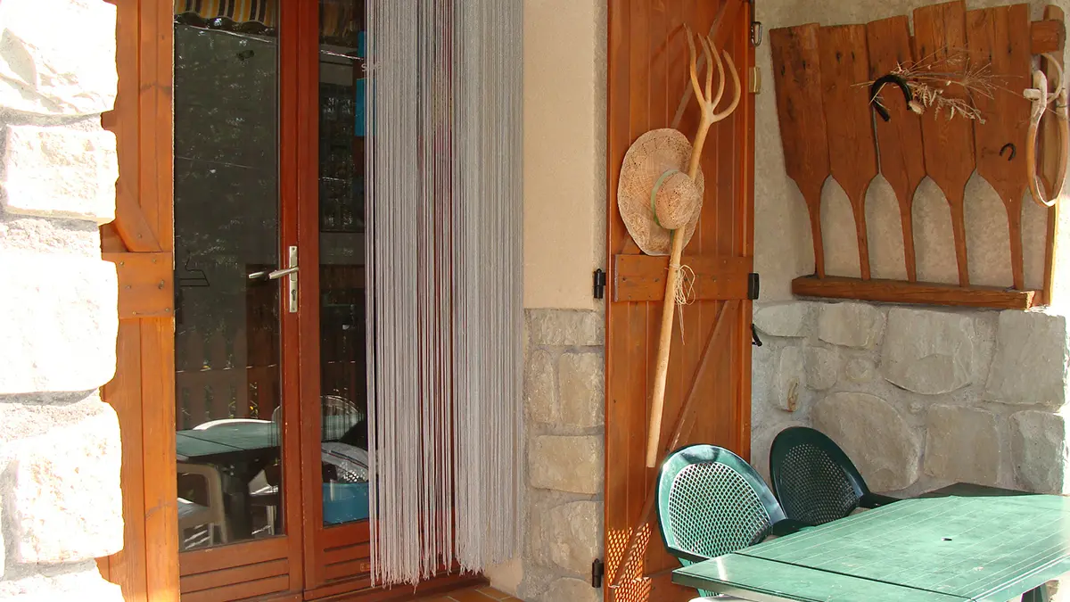 Terrasse extérieure d'une maison en pierre, table d'extérieur, porte-fenêtre