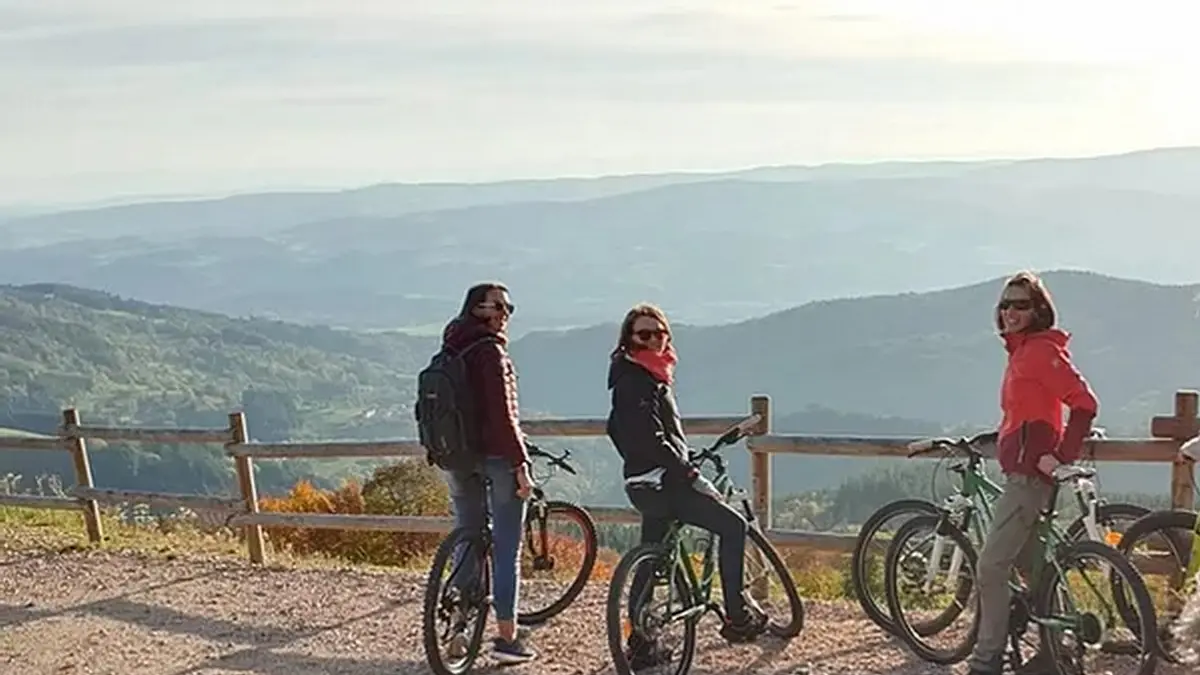 Un groupe d'adulte découvre les Hautes-Chaumes en VTT et admire la vue imprenable depuis le Col des Supeyres