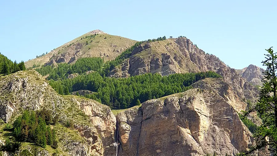 Vue à distance de la cascade du Pich, coulant le long d'une crevasse rocheuse, entourée de forêts au-dessous et au-dessus