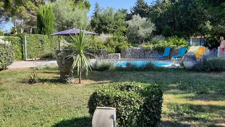 Jardin exterieur devant le gîte avec piscine et transat.