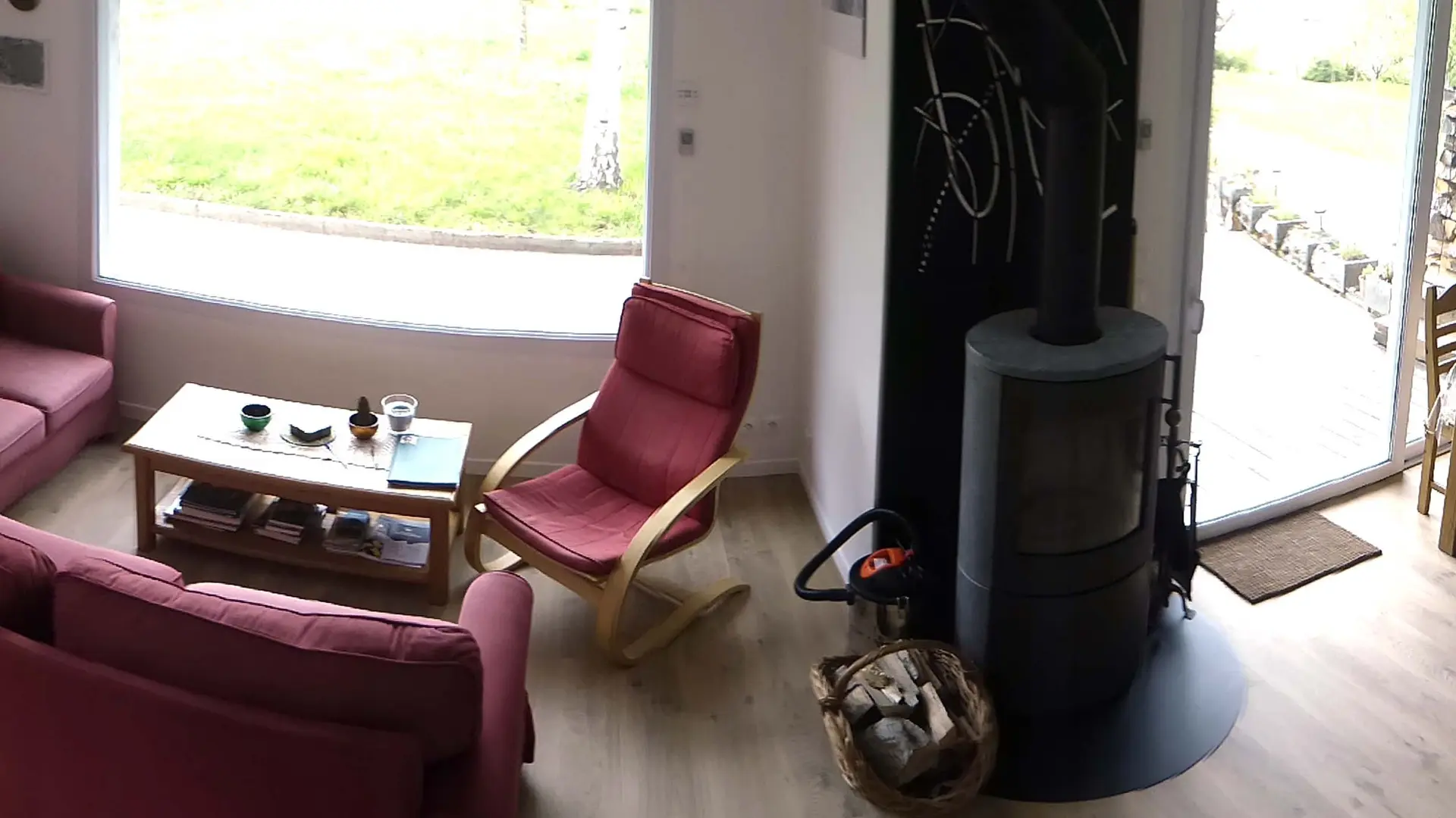 Espace salon avec 2 canapé, un fauteuil et un poêle à bois, salle à manger avec une table et des chaises en bois