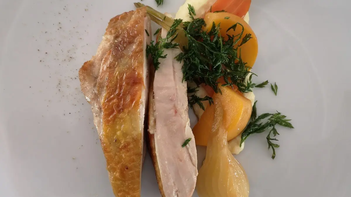 Plat chaud avec du poulet et une purée sur laquelle sont déposés quelques légumes rôties.