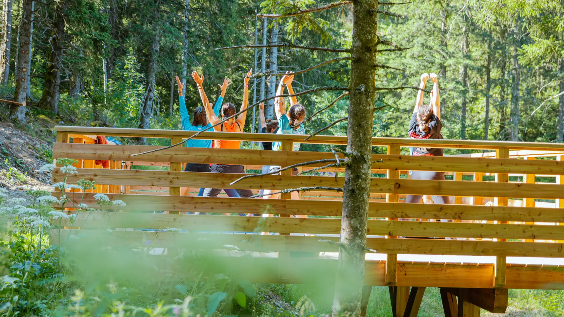 Un groupe de personnes fait une séance de yoga sur la plateforme en bois de Bédina au coeur de la nature