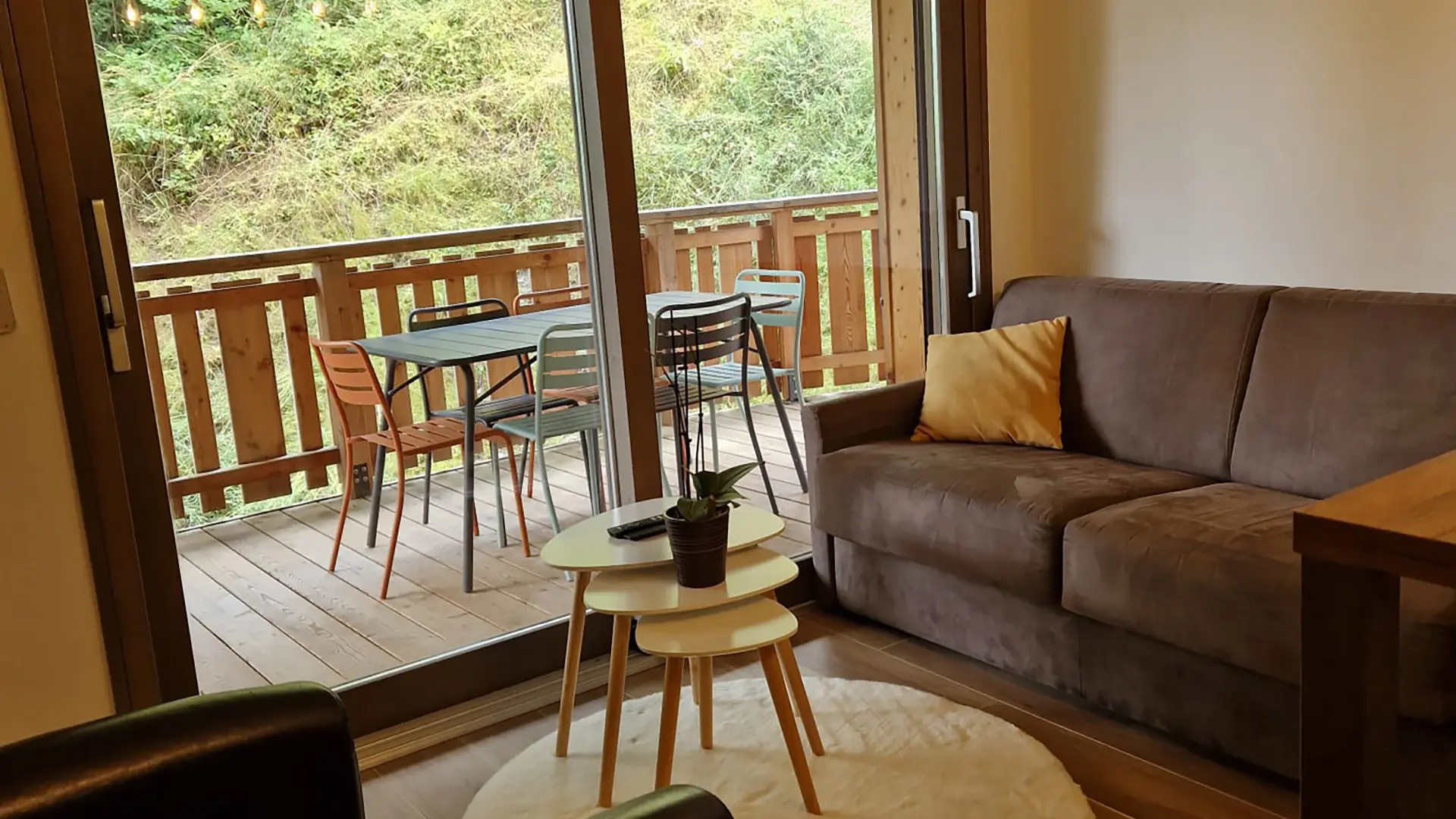 Salon avec canapé convertible, fauteuil ,table basse, baie vitrée donnant accès à la terrase