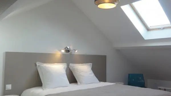 Notre espace nuit mansardé avec parquet proposant une literie grand confort et du mobilier design.