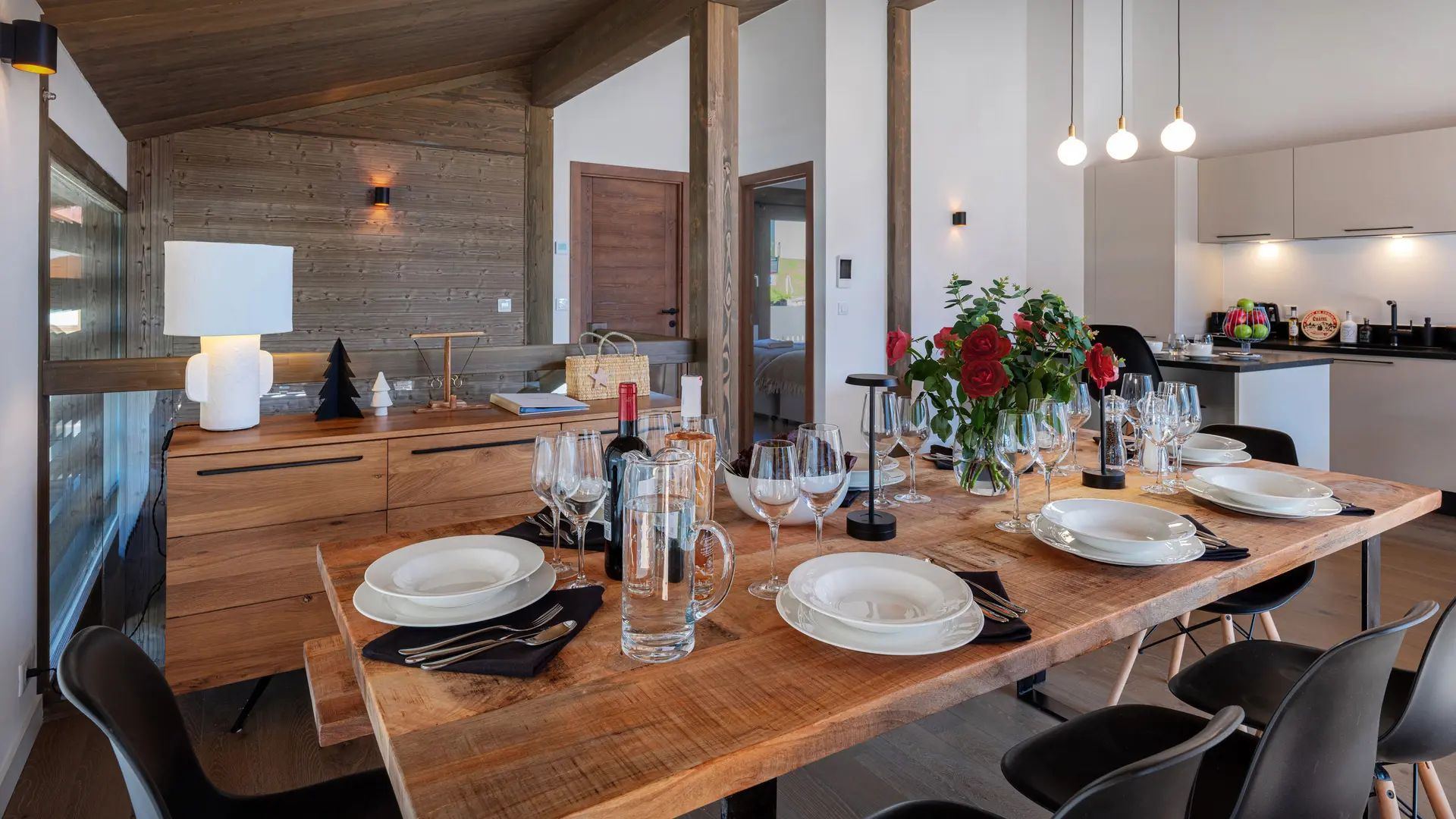 Salle à manger avec table dressée et cuisine en arrière plan