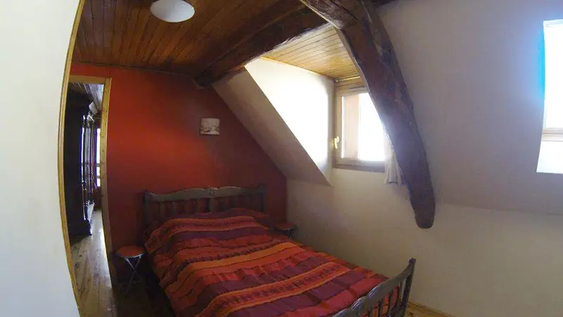 Attic bedroom with double bed, wooden furniture, parquet flooring, window