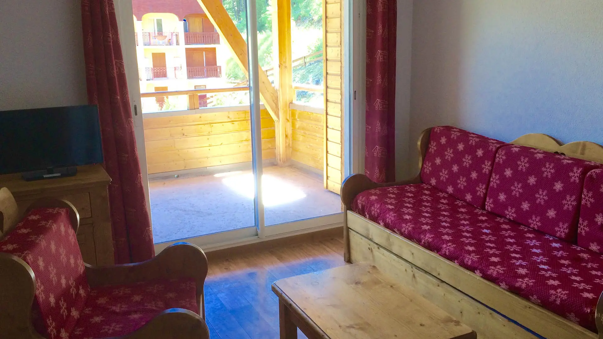 Bright apartment living room with sofa, armchair, coffee table, French doors opening onto a terrace