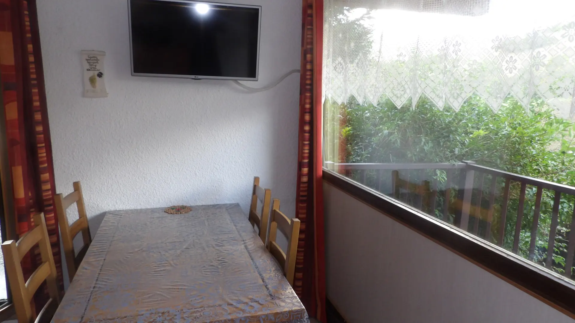 Table à manger pour 4 personnes à côté d'une grande baie lumineuse qui donne sur le balcon