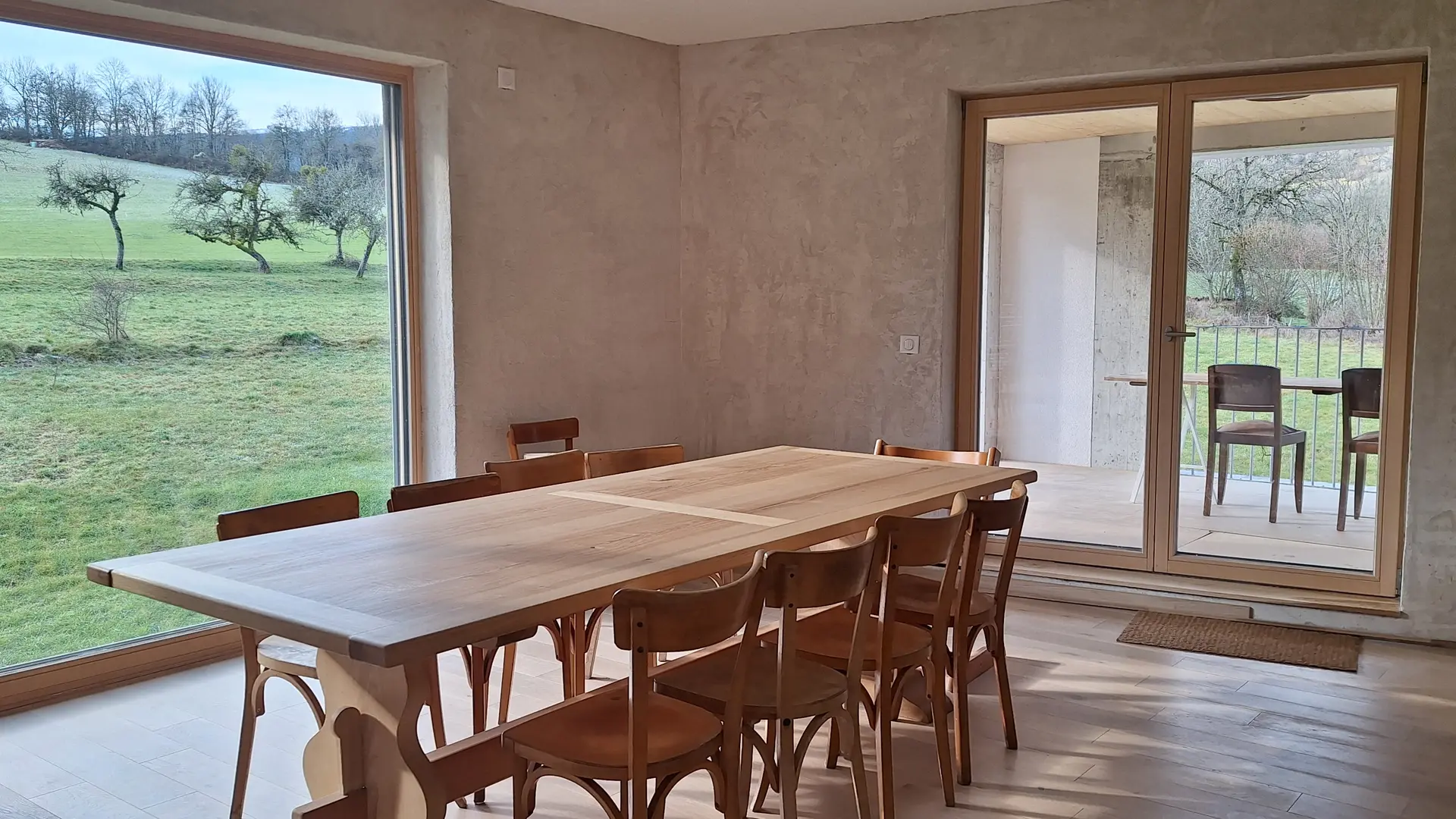 Belle table et chaises en bois face à la baie vitrée