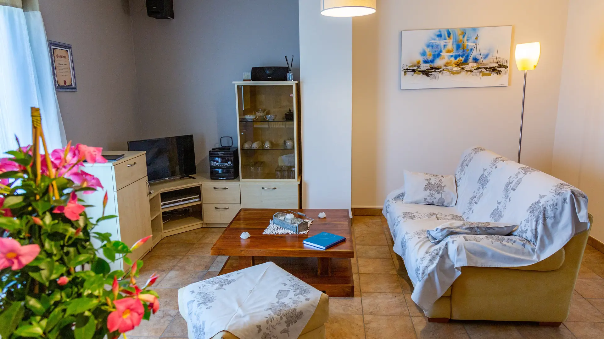 Un salon confortable et lumineux, aménagé pour des moments de détente, avec coin télévision et décoration chaleureuse.