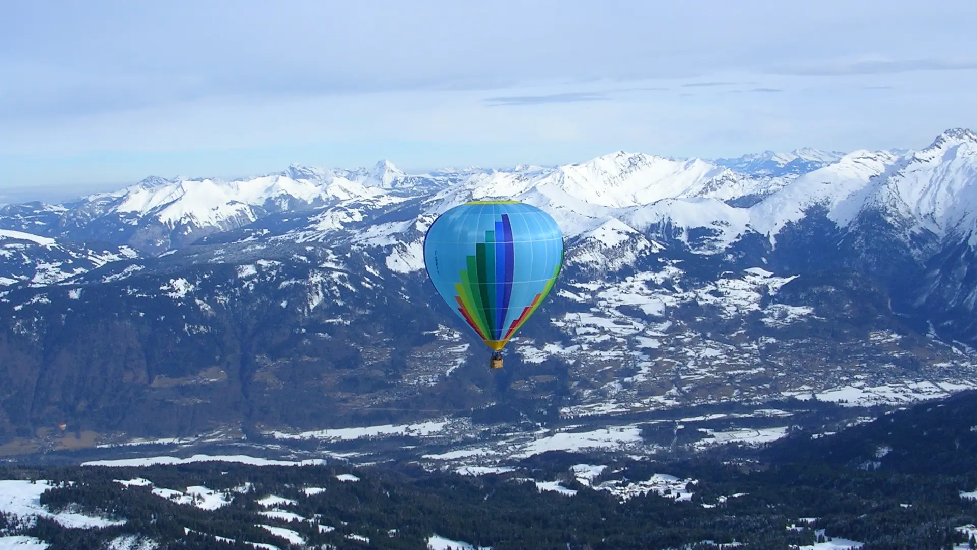 Montgolfière en vol hivernal avec vue sur la vallée enneigée
