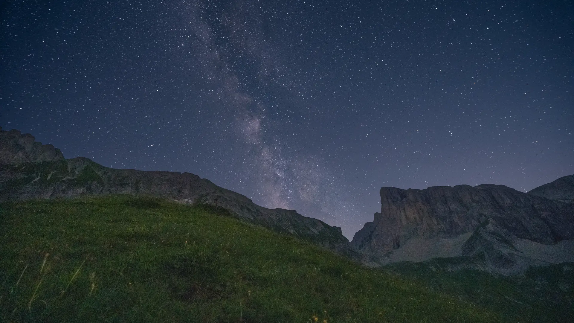 Le paysage offre une vue sur le ciel étoilé, avec des variations tandis qu'en dessous, on aperçois des montagnes.