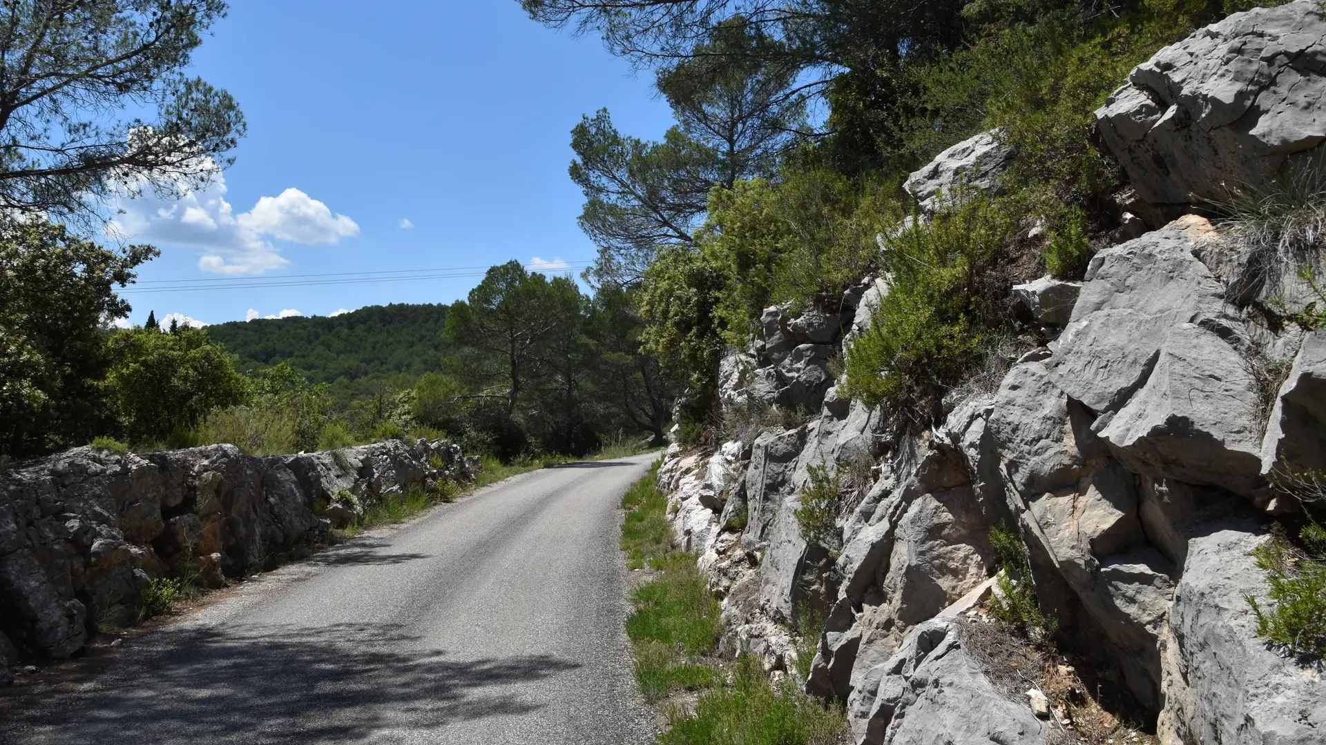 Portion de route entourée de rochers et avec une vue sur les collines verdoyantes environnantes
