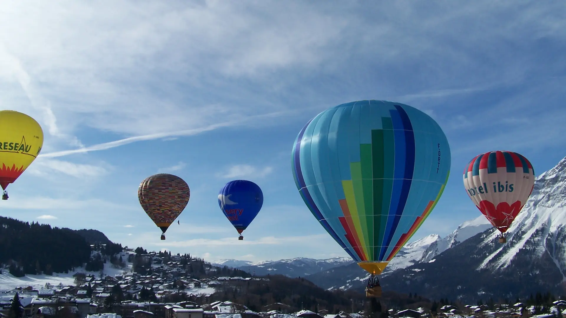 Plusieurs montgolfières survolant le village des Carroz d'Arâches en hiver