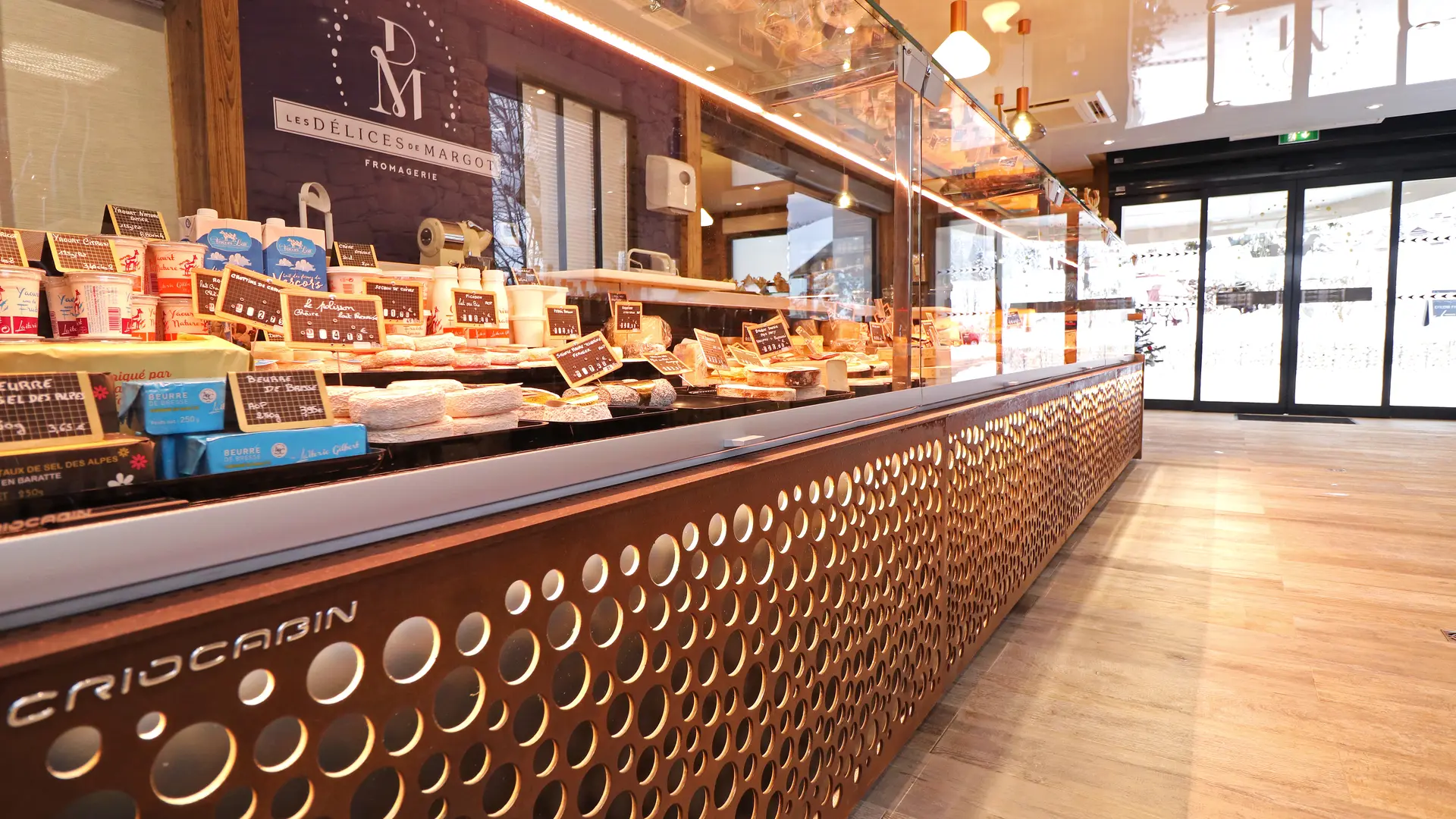 Comptoir de présentation des fromages, avec la porte d'entrée en arrière plan.