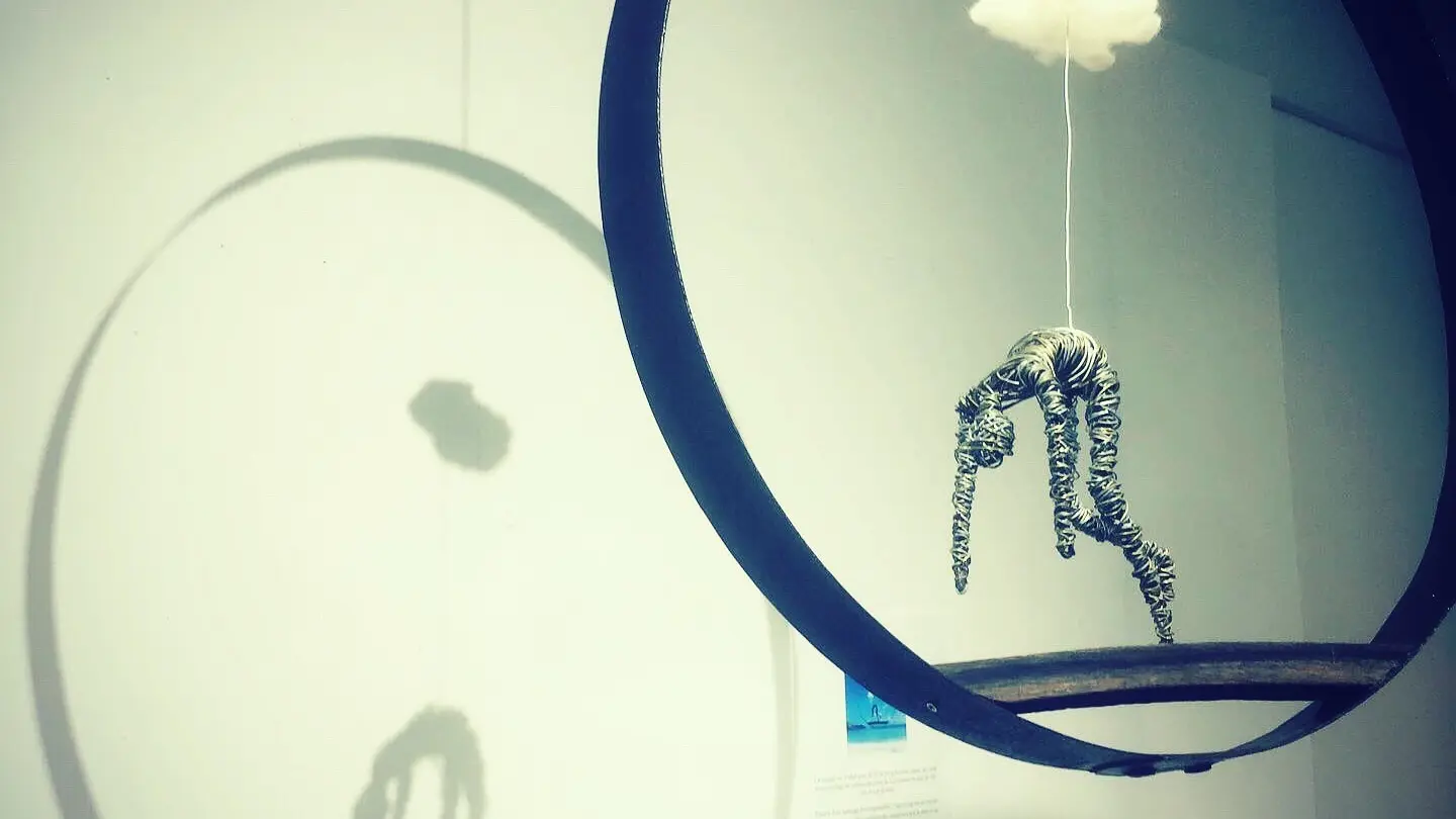 Le Zinglé_L'Isle-sur-la-Sorgue sculpture personnage en fil de fer suspendu en dessous d'un petit nuage dans un cerclage métal