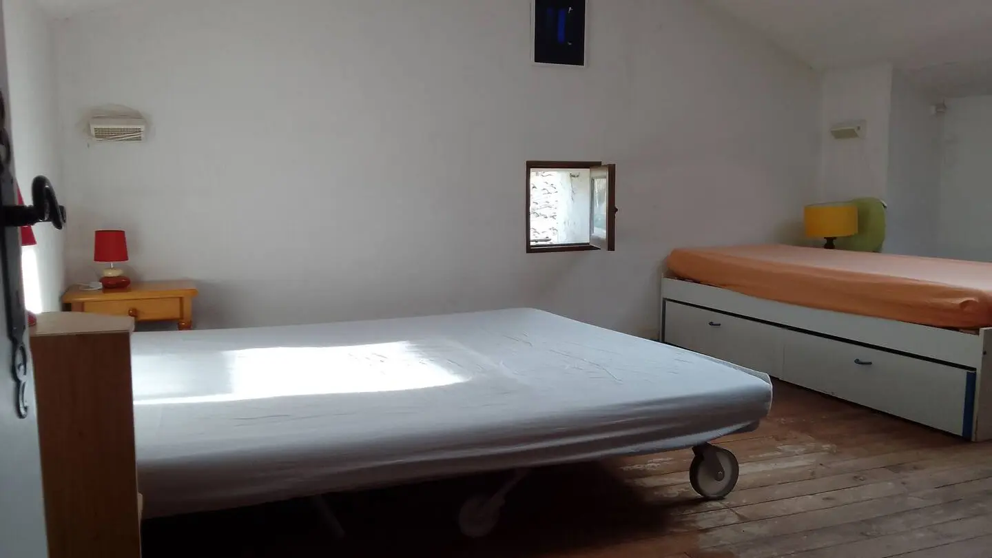 Chambre 5, en sous-pente, qui fait office de dortoir avec un canapé lit pour deux personnes et deux lits simples