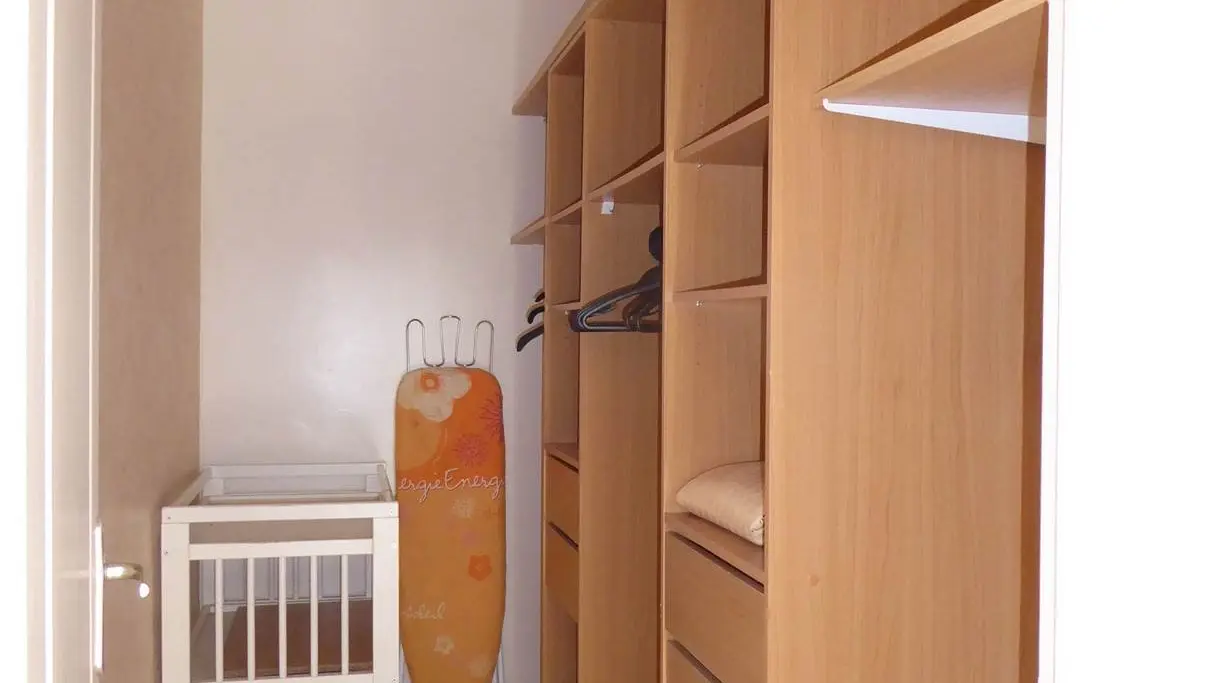 Un dressing avec à droite, une grande armoire en bois occupe une grande partie de la pièce.