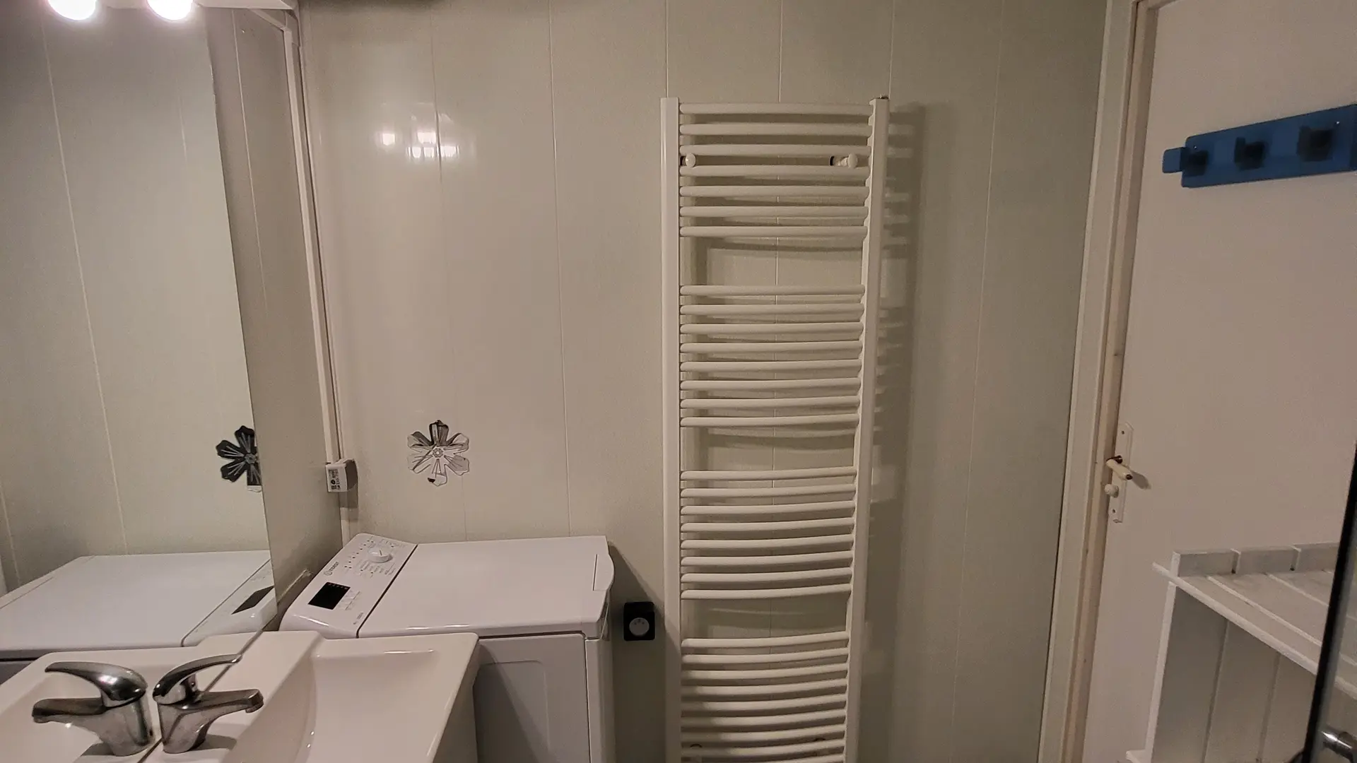 Cette salle de bain est équipée d'un lavabo, et d'un lave-linge.
