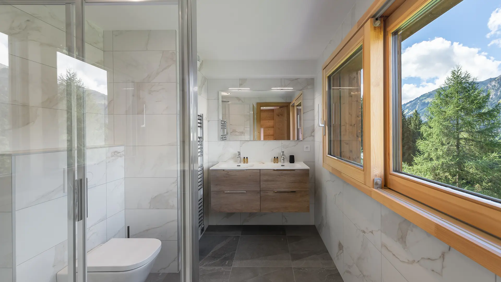 Salle de bains avec double vasque et son meuble, miroir, fenêtre, toilettes