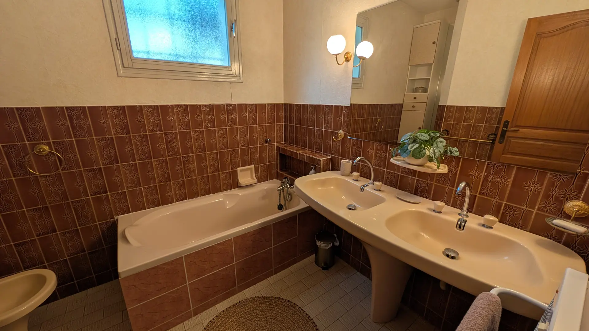 Une salle de bain carrelée de marron avec une baignoire, un lavabo et des toilettes.