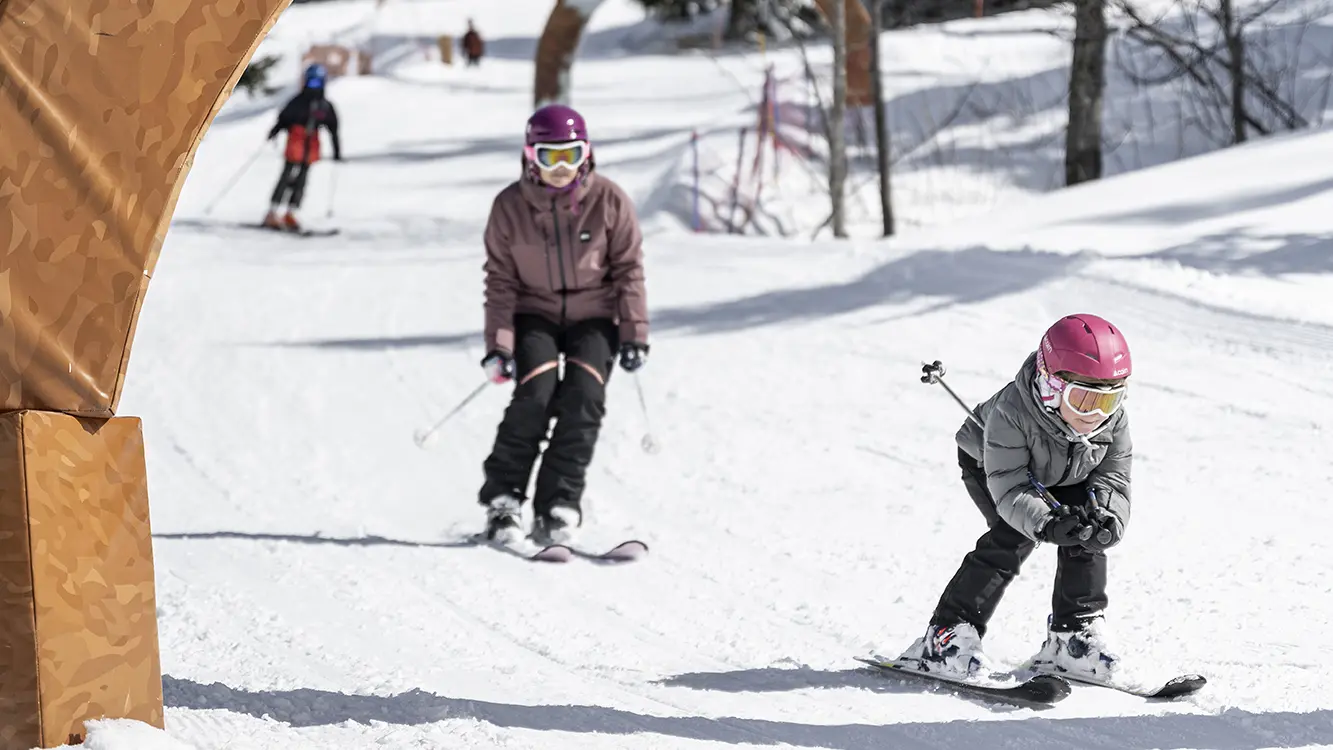 Enfants skiant sur la piste Défi Môm', piste pour les débutants sur le domaine de ski alpin du Grand-Bornand