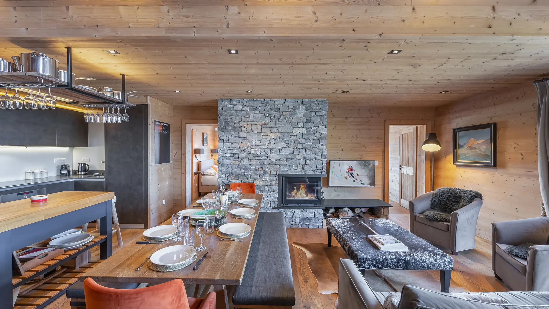 Espace salle à manger dans pièce à vivre ouverte, grande table avec bancs et fauteuil, cheminée
