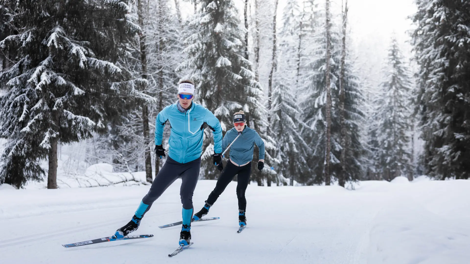 Deux skieurs sur une piste de ski nordique à travers les sapins au Grand-Bornand
