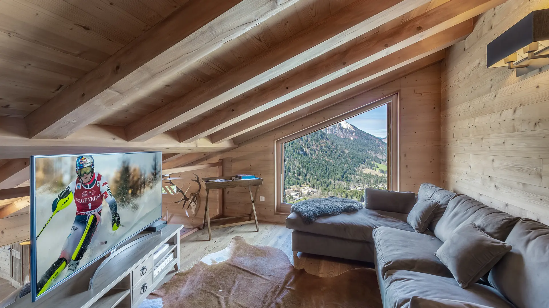 Espace télévision avec grand canapé, fenêtre, poutres apparentes