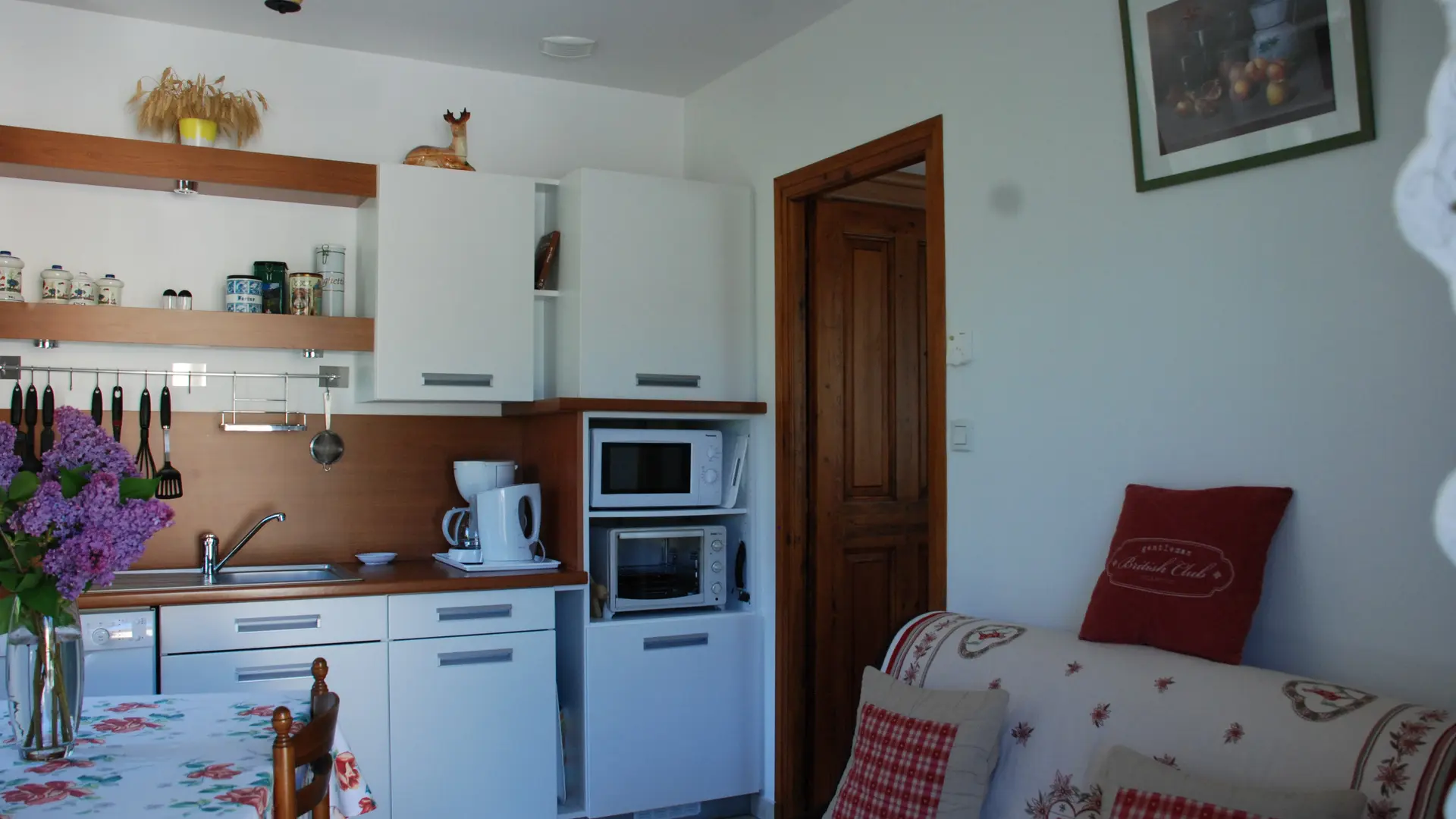 C'est une pièce à vivre ouverte où se trouvent une cuisine fonctionnelle avec des placards et un espace détente avec un canapé. Une table et des chaises permettent de manger dans cet espace.